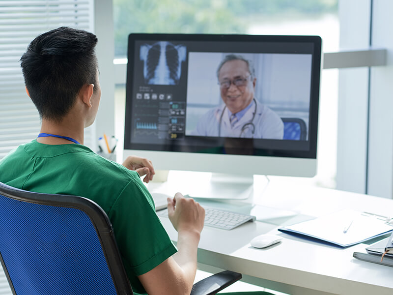 Junger Arzt spricht über Videocall mit Kollegen über Telemedizin und digitaler Patientenakte
