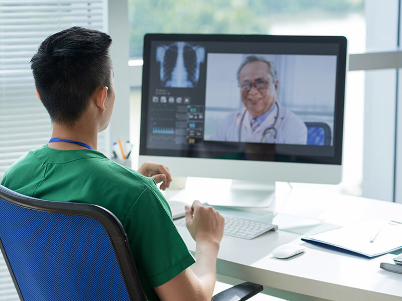 Junger Arzt spricht über Videocall mit Kollegen über Telemedizin und digitaler Patientenplattform